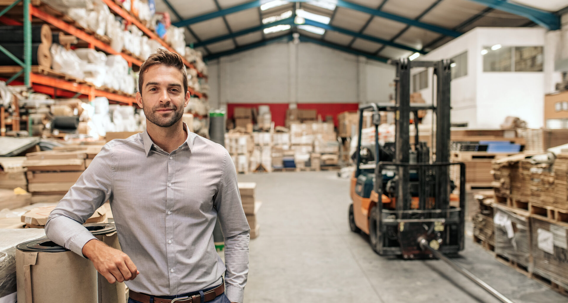 Geschäftsführer eines mittelständischen Unternehmens im Lager mit Hochregalen und Gabelstapler – Stromeinkauf für Unternehmen mit hohem Energiebedarf | Foto: iStock/mavo