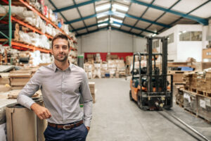 Geschäftsführer eines mittelständischen Unternehmens im Lager mit Hochregalen und Gabelstapler – Stromeinkauf für Unternehmen mit hohem Energiebedarf | Foto: iStock/mavo