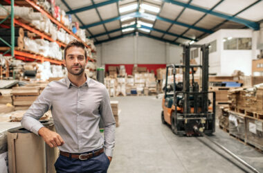 Geschäftsführer eines mittelständischen Unternehmens im Lager mit Hochregalen und Gabelstapler – Stromeinkauf für Unternehmen mit hohem Energiebedarf | Foto: iStock/mavo